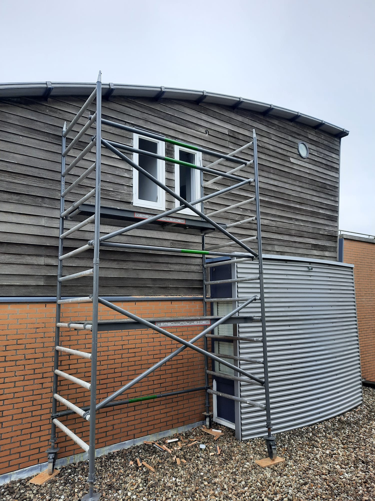 VerbouwNow aan het werk in Leiden: steiger bij houten gevel met VerbouwNow-branding